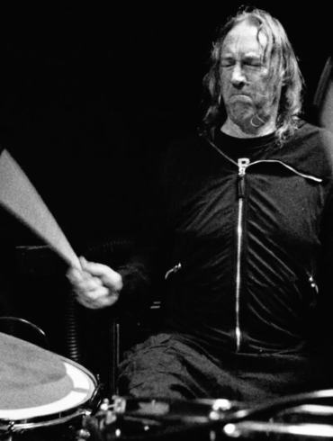 Danny Carey de Tool tocando en un escenario oscuro.